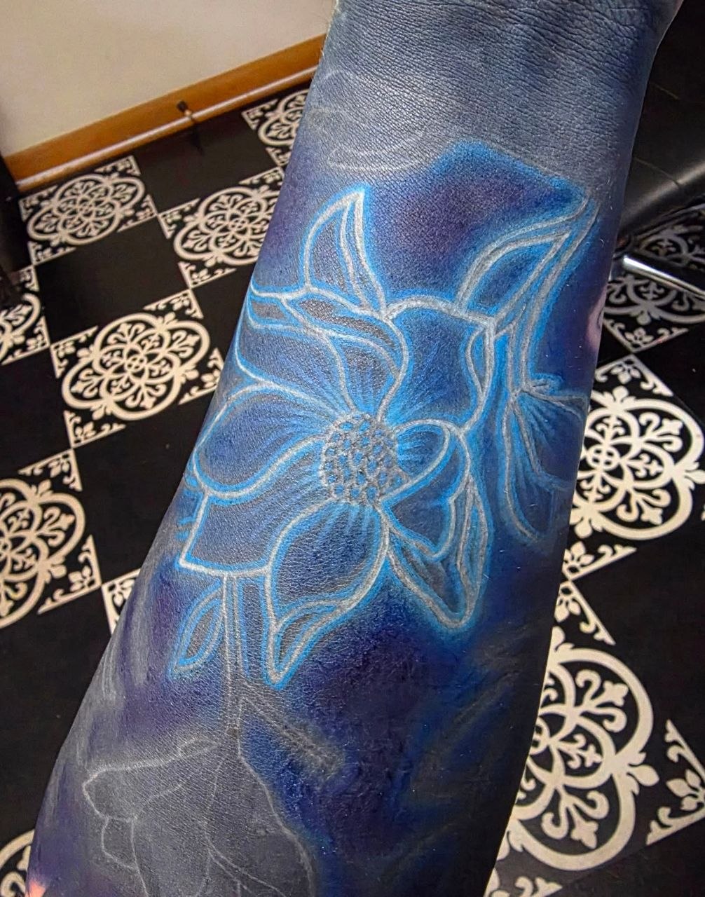 Blue wash floral forearm tattoo with fine line work